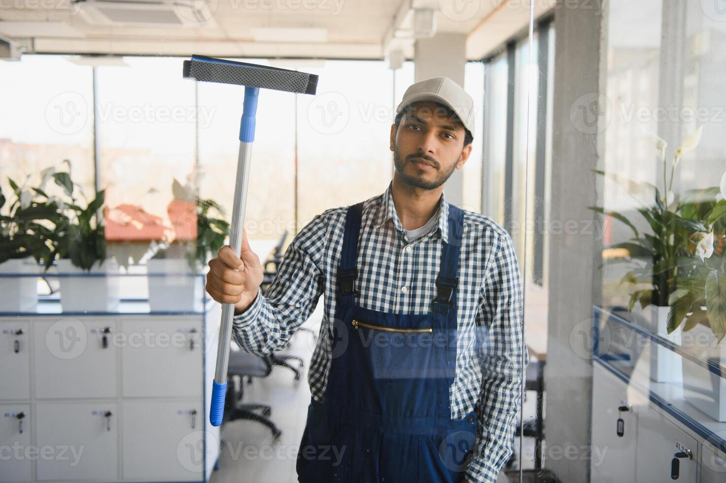 jovem indiano homem lavando janela dentro escritório. foto