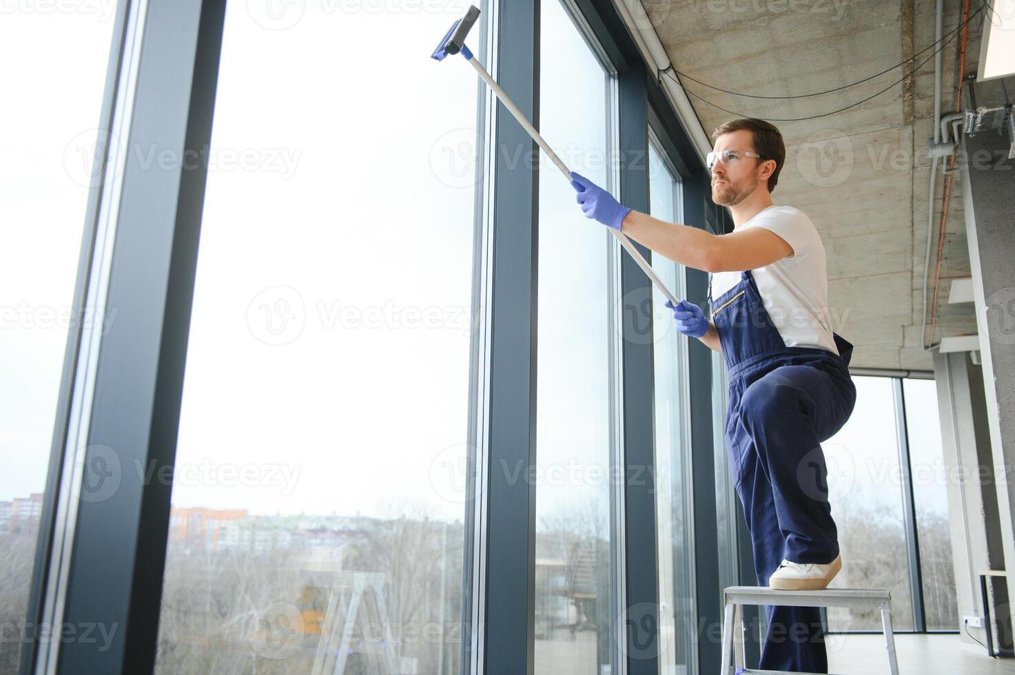 masculino profissional limpeza serviço trabalhador dentro macacão limpa a janelas e fazer compras janelas do uma loja com especial equipamento. foto