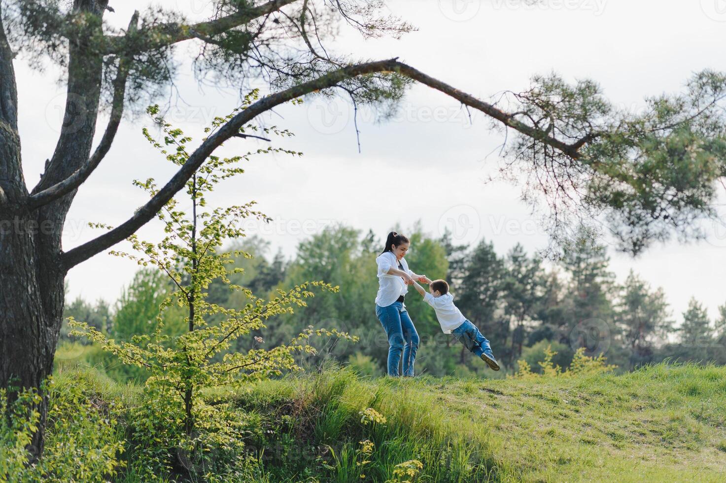 feliz jovem mãe é jogando com dela bebê dentro uma parque em uma verde grama. felicidade e harmonia do família vida. ótimo família período de férias. Boa fim de semana. mães dia. feriado. a conceito do uma feliz família foto