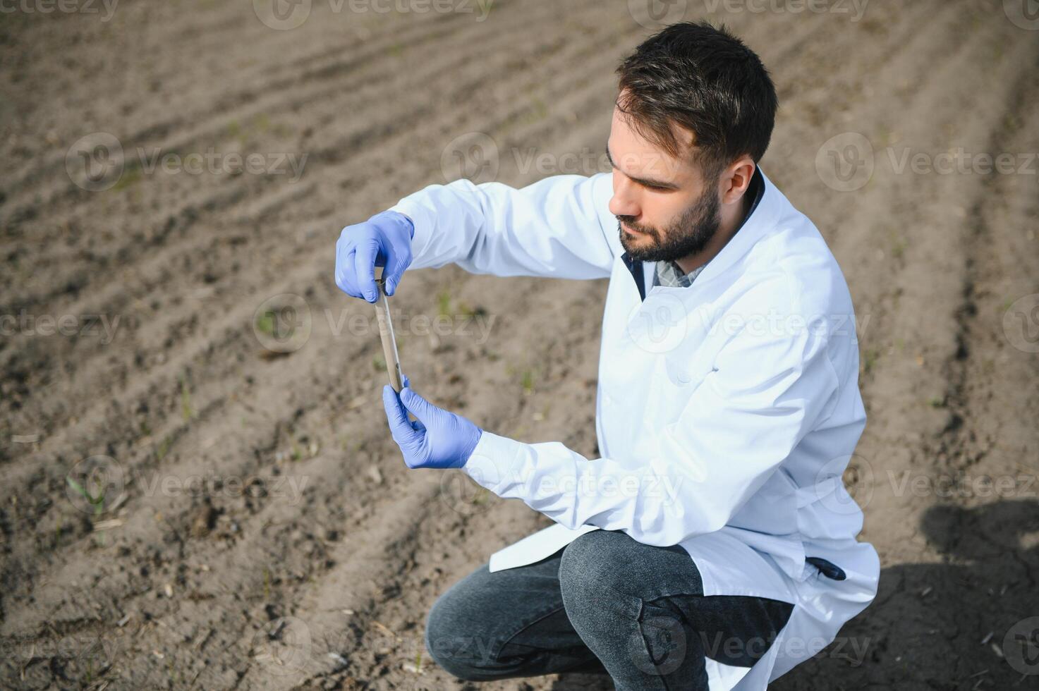 laboratório trabalhador segurando profissional artigos de vidro e teste Preto solo depois de colheita dentro a campo foto