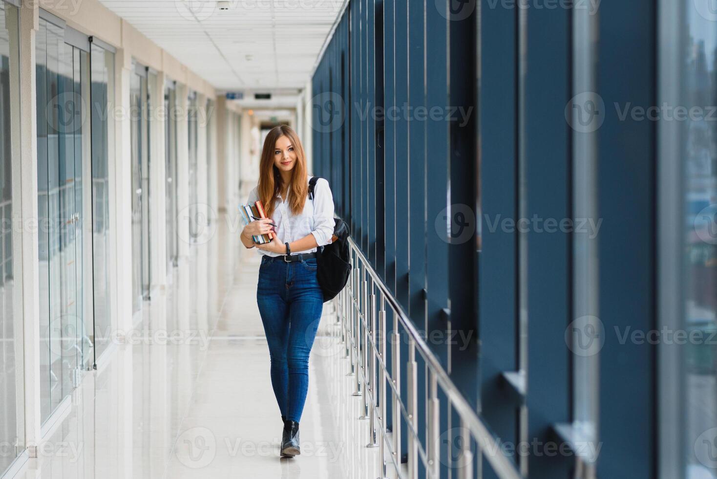 retrato do uma bonita fêmea aluna com livros e uma mochila dentro a universidade corredor foto