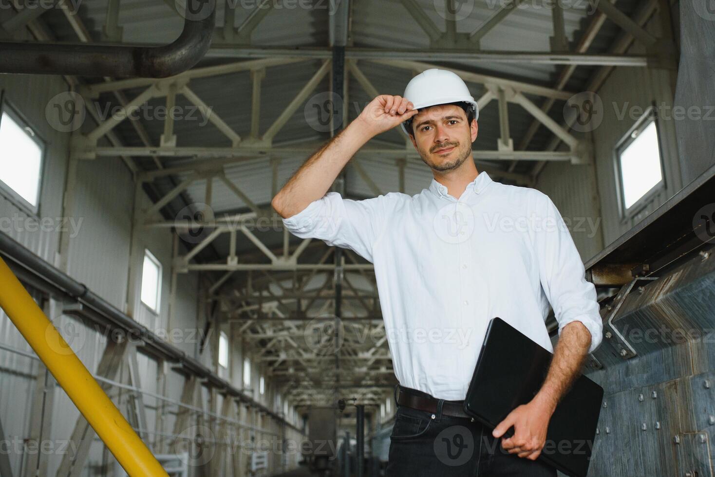 uma jovem bonito empregado do uma moderno fábrica dentro uma branco duro. dentro a fundo é uma ampla fazer compras para a Produção. foto