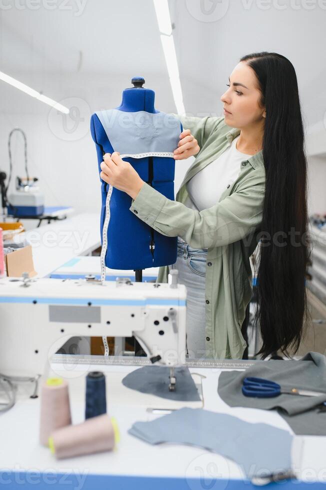 jovem mulher trabalhando Como costureira dentro roupas fábrica. foto