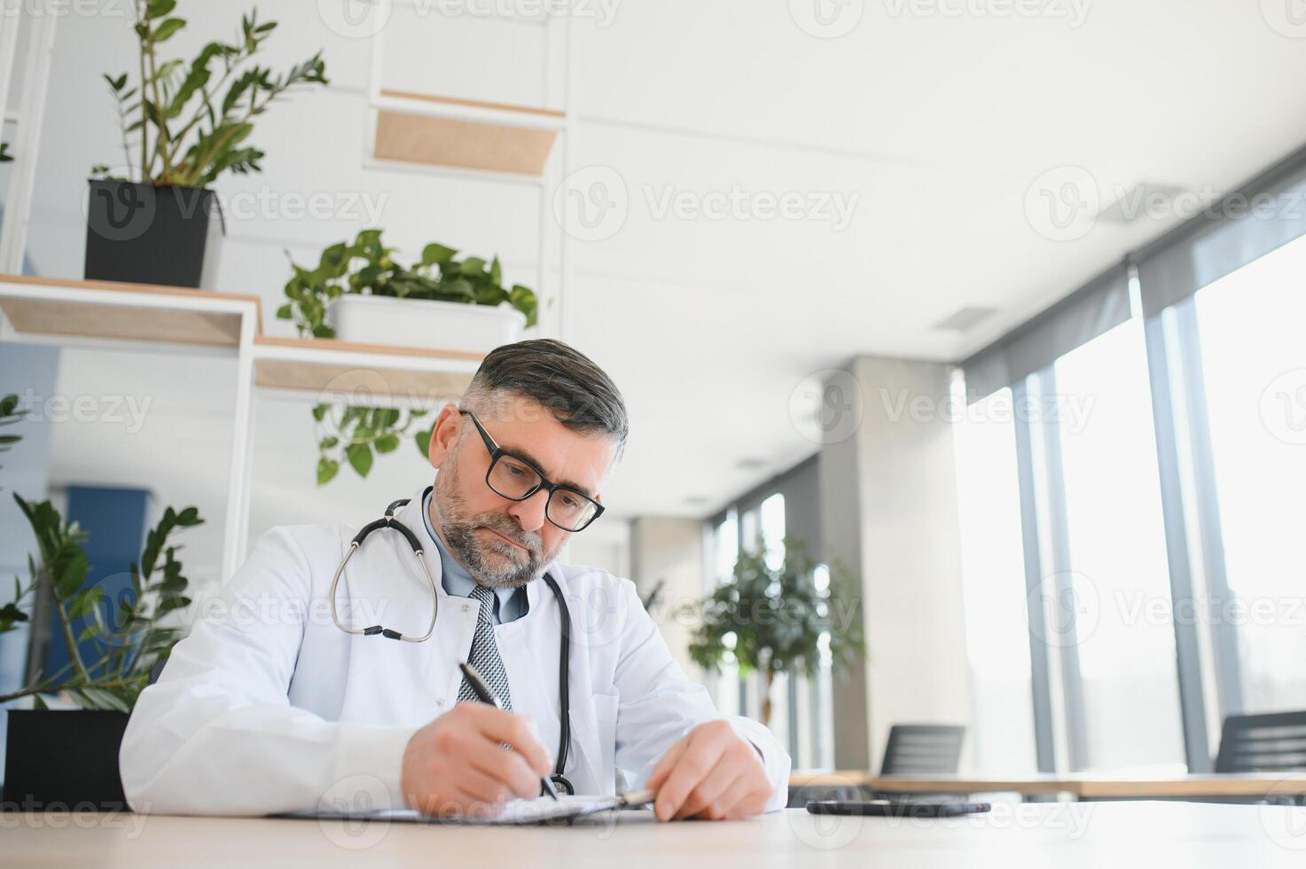 Senior doutor, escrevendo e retrato do uma hospital trabalhador dentro uma escritório fazendo médico pesquisar. felicidade, computador portátil e lista de controle do uma bem estar e saúde empregado com uma sorrir a partir de clínica visão foto