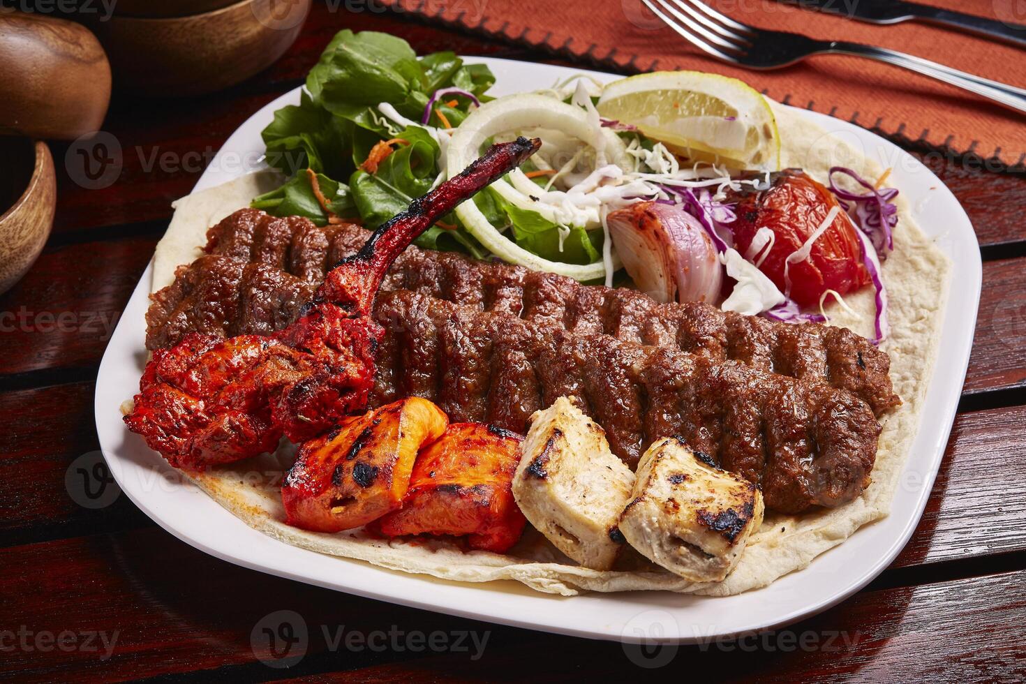 misturado tandoori grelha prato com tikka boti kabab, salada, limão e pão servido dentro prato isolado em mesa lado Visão do meio leste Comida foto