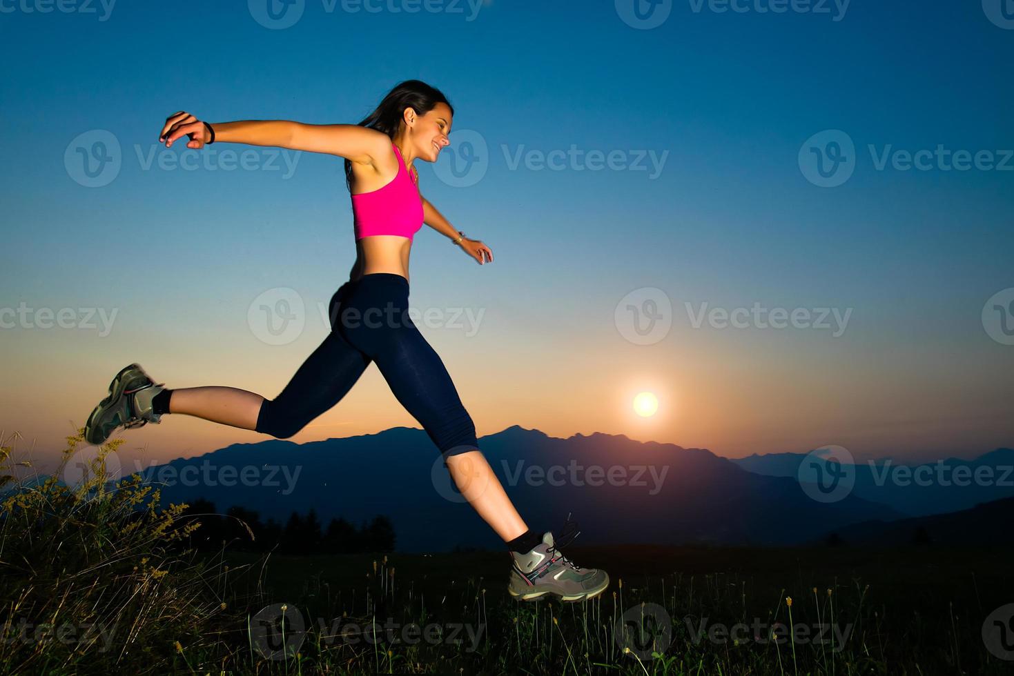 garota pulando ao pôr do sol nas montanhas foto