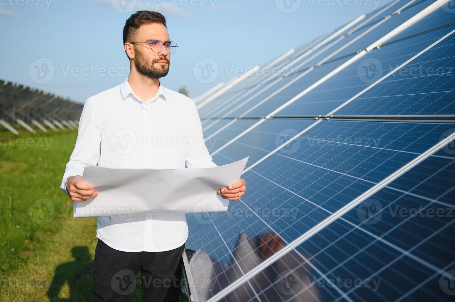 positivo barbudo masculino investidor em pé contra fotovoltaico painéis produzindo alternativo energia. foto