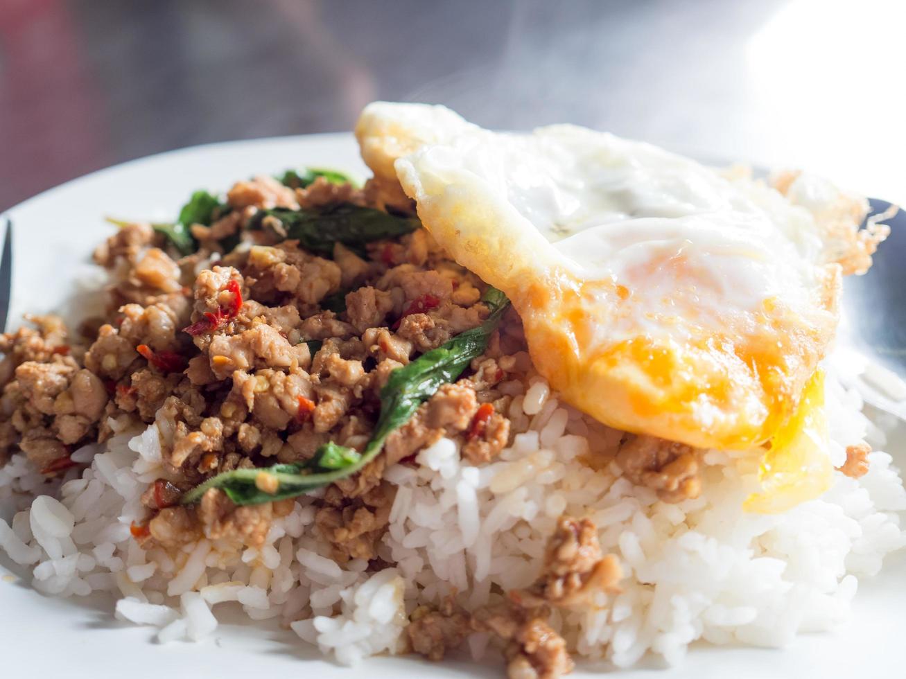 arroz tailandês local coberto com manjericão de porco frito e ovo frito. foto