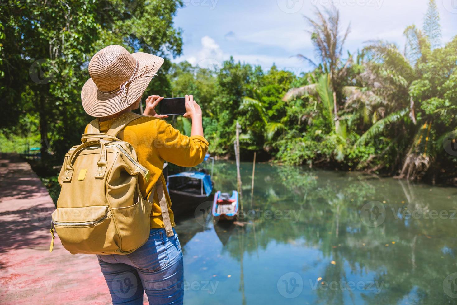 mulher asiática viajar natureza. viajar relaxar. usando o telefone celular, tire uma foto de barco da bela natureza em tha pom-klong-song-nam. Krabi, viaje na Tailândia.