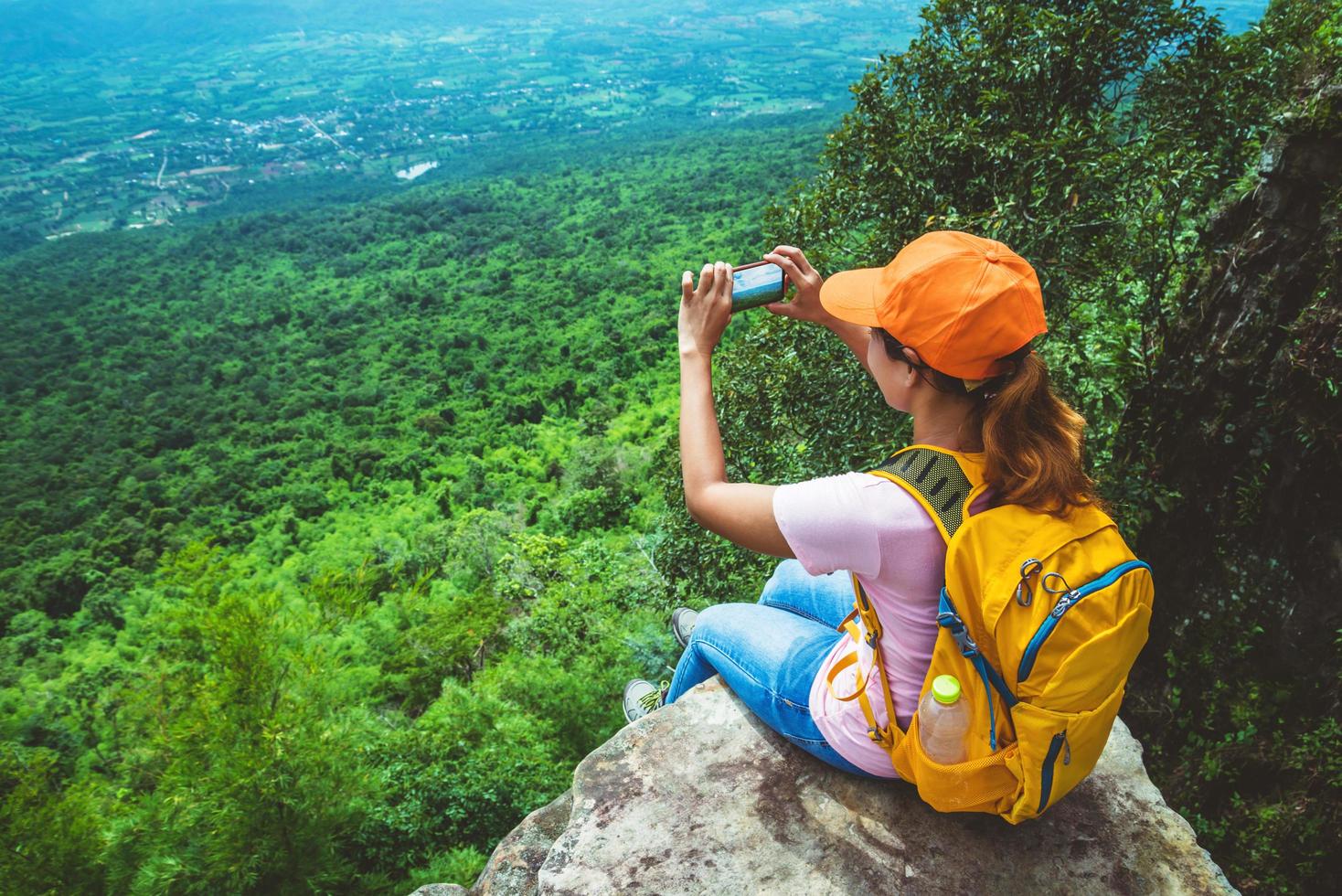 mulheres asiáticas viajam relaxam no feriado. sente-se e tire uma foto no penhasco.