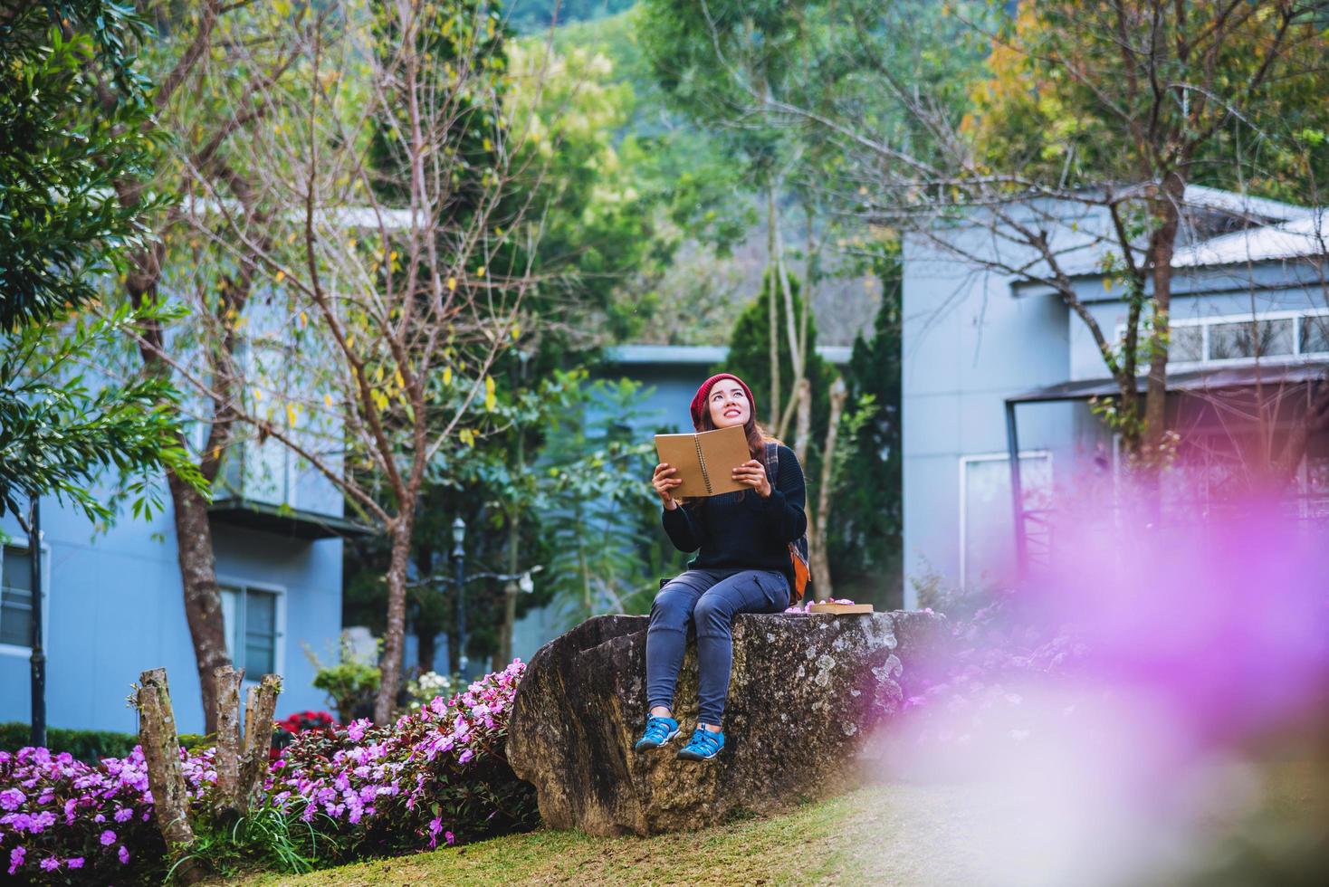 mulher viajar natureza no jardim de flores. relaxe sentado nas pedras e lendo livros em meio à natureza no parque nacional doi inthanon. foto