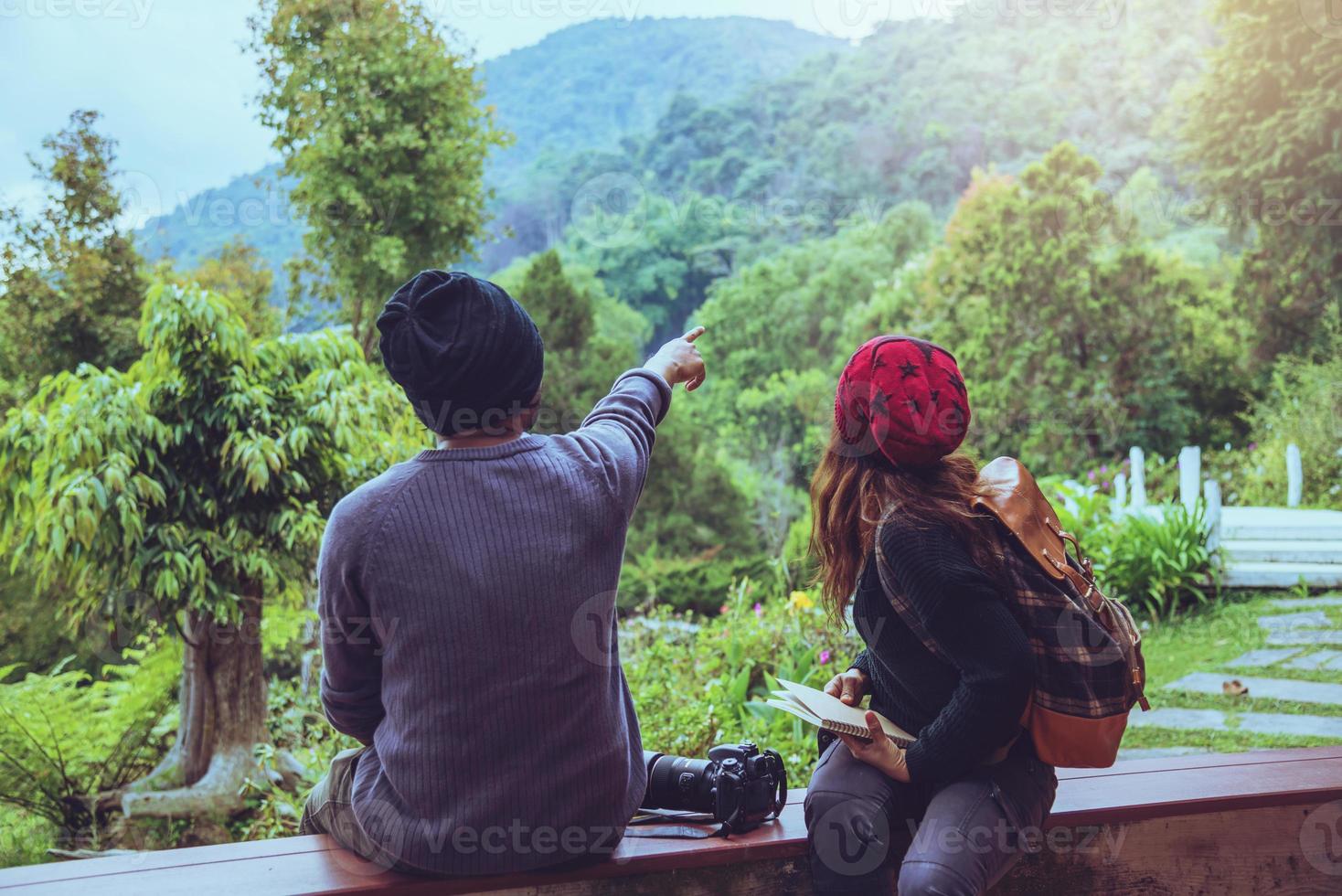 casal asiático viajar fotografia natureza educação. natureza relaxar e estudar ler um livro. no parque público. Na Tailândia foto