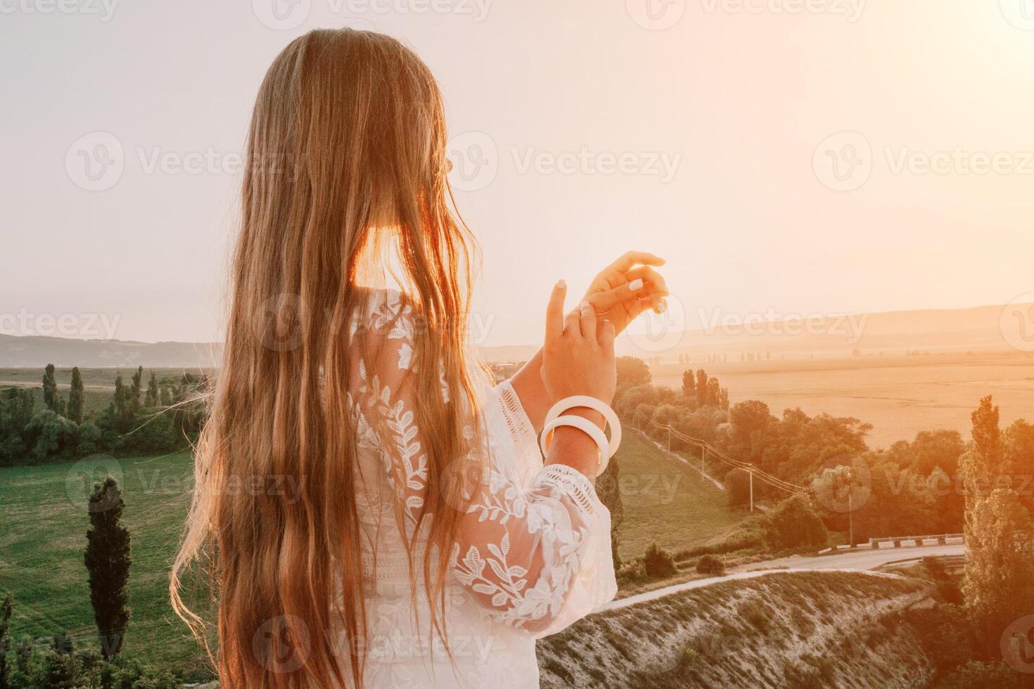 feliz mulher dentro branco boho vestir em pôr do sol dentro montanhas. romântico mulher com grandes cabelo em pé com dela costas em a pôr do sol dentro natureza dentro verão com aberto mãos. silhueta. natureza. pôr do sol. foto