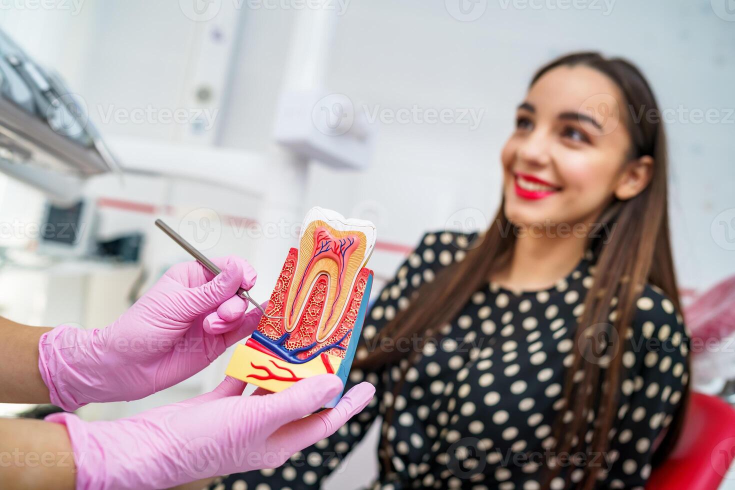 médico mostra em uma plástico dente amostra ou modelo diferente métodos do dentes tratamento. paciente em borrado fundo. saúde conceito. Rosa médico luvas em fêmea médico mãos. foto