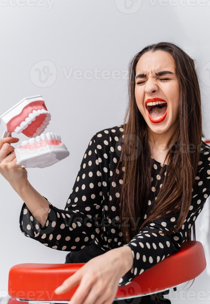 mulher com fechadas olhos e aberto boca. jovem menina segurando aberto educacional dentista mandíbula perto face. dental conceito. engraçado emoções. foto