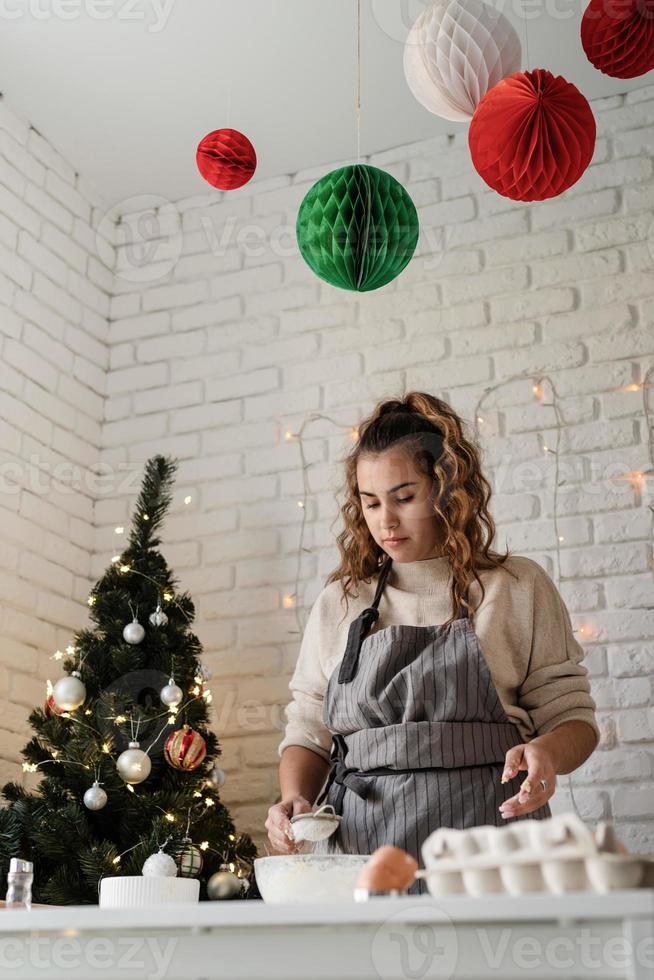 mulher sorridente na cozinha fazendo biscoitos de natal foto