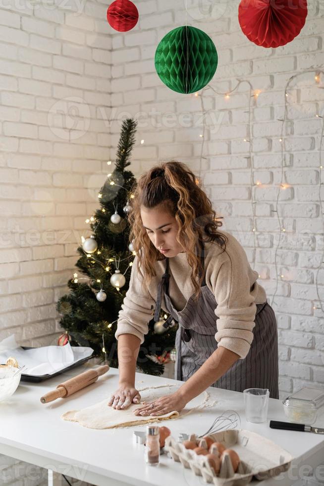 mulher sorridente na cozinha fazendo biscoitos de natal foto