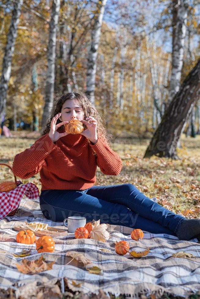 Mulher bonita em um suéter vermelho em um piquenique em uma floresta de outono foto