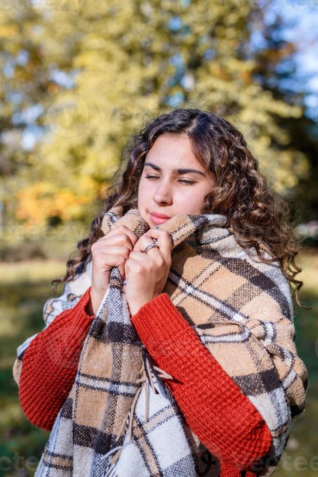 retrato de uma jovem mulher feliz em uma manta quente na floresta de outono foto