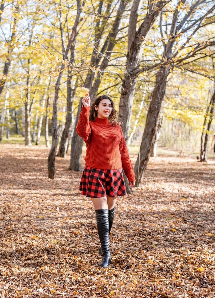 jovem mulher feliz caminhando na floresta de outono foto