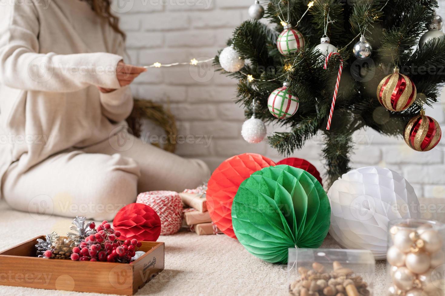 jovem mulher atraente decorando a árvore de natal com luzes de fada foto