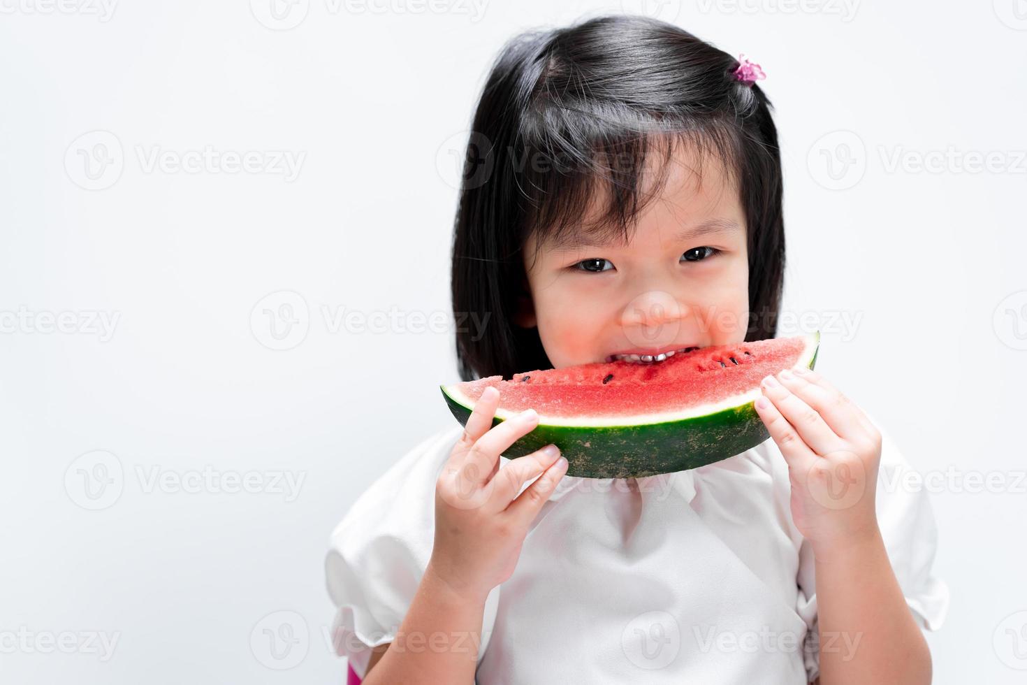 menina adorável criança asiática mordida para comer melancia. em fundo branco isolado. foto