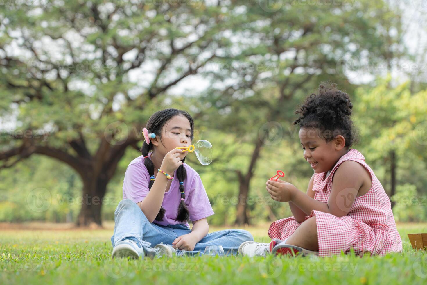 crianças sentado dentro a parque com sopro ar bolha, cercado de vegetação e natureza foto