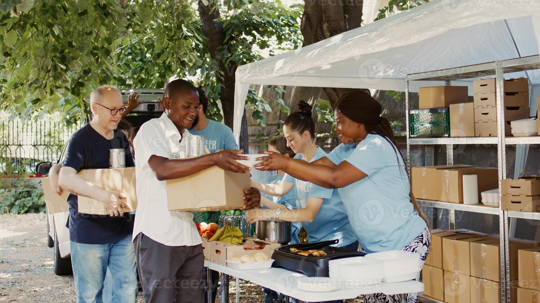 carente indivíduos estão forneceu com refeição caixas e enlatado bens de dedicada voluntários. sorridente caridade trabalhadores representando a Comida dirigir e sem fins lucrativos organização alimentação a sem teto pessoas. foto