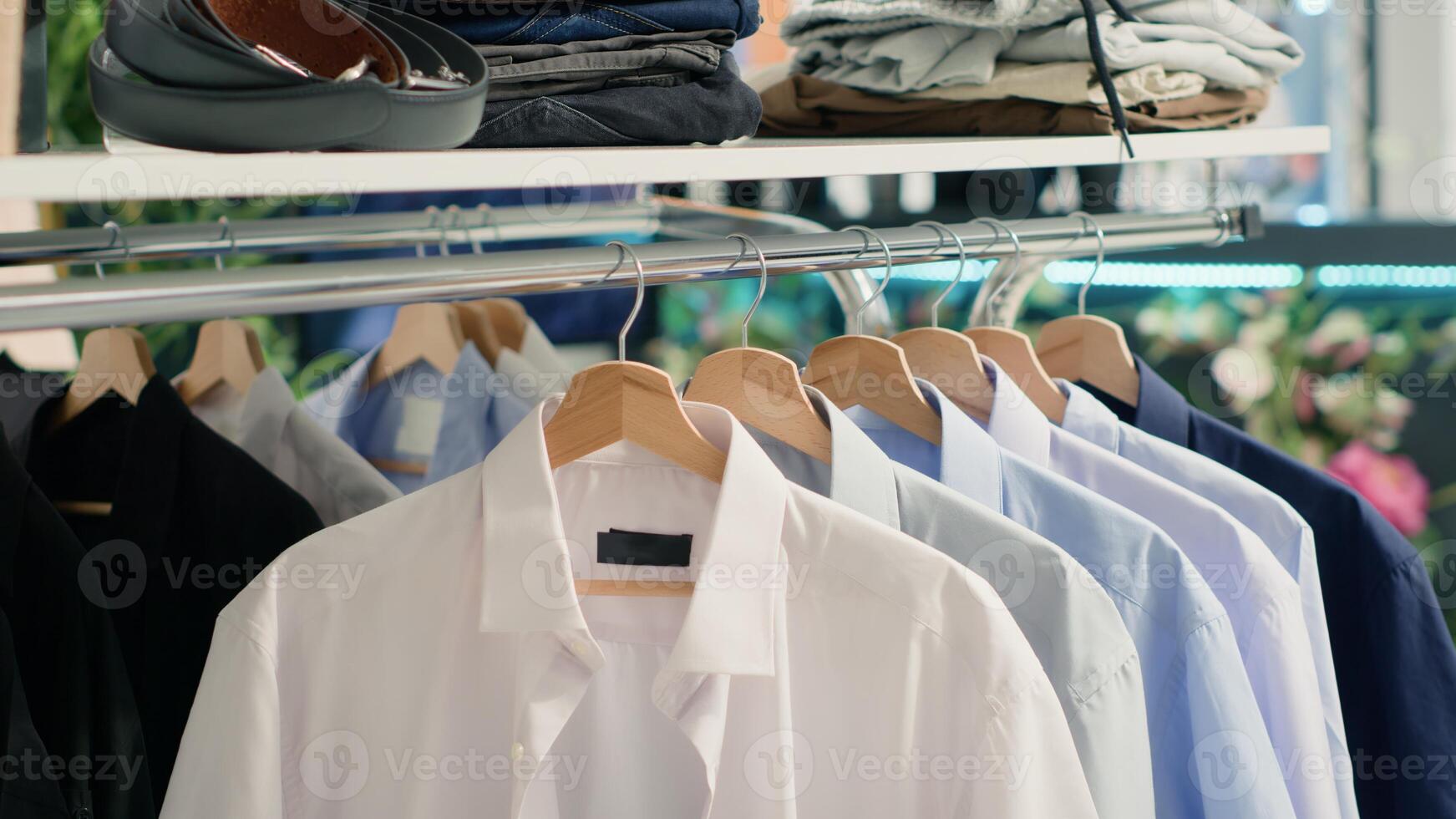 panning tiro do à moda formal roupas em cabide dentro esvaziar chique moda boutique. Mais recentes requintado desenhador roupas homens camisas coleção dentro Prêmio showroom, fechar acima tomada. foto