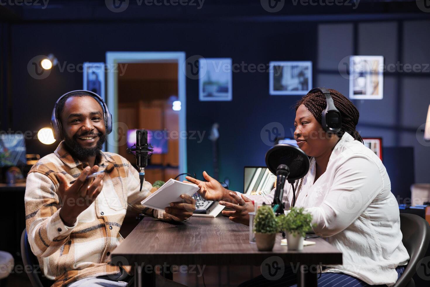 barbudo homem risos durante uma comédia podcast Como a hospedeiro piadas por aí com africano americano fêmea blogueiro. masculino jornalista entretém ambos a convidado e público assistindo a partir de lar. foto