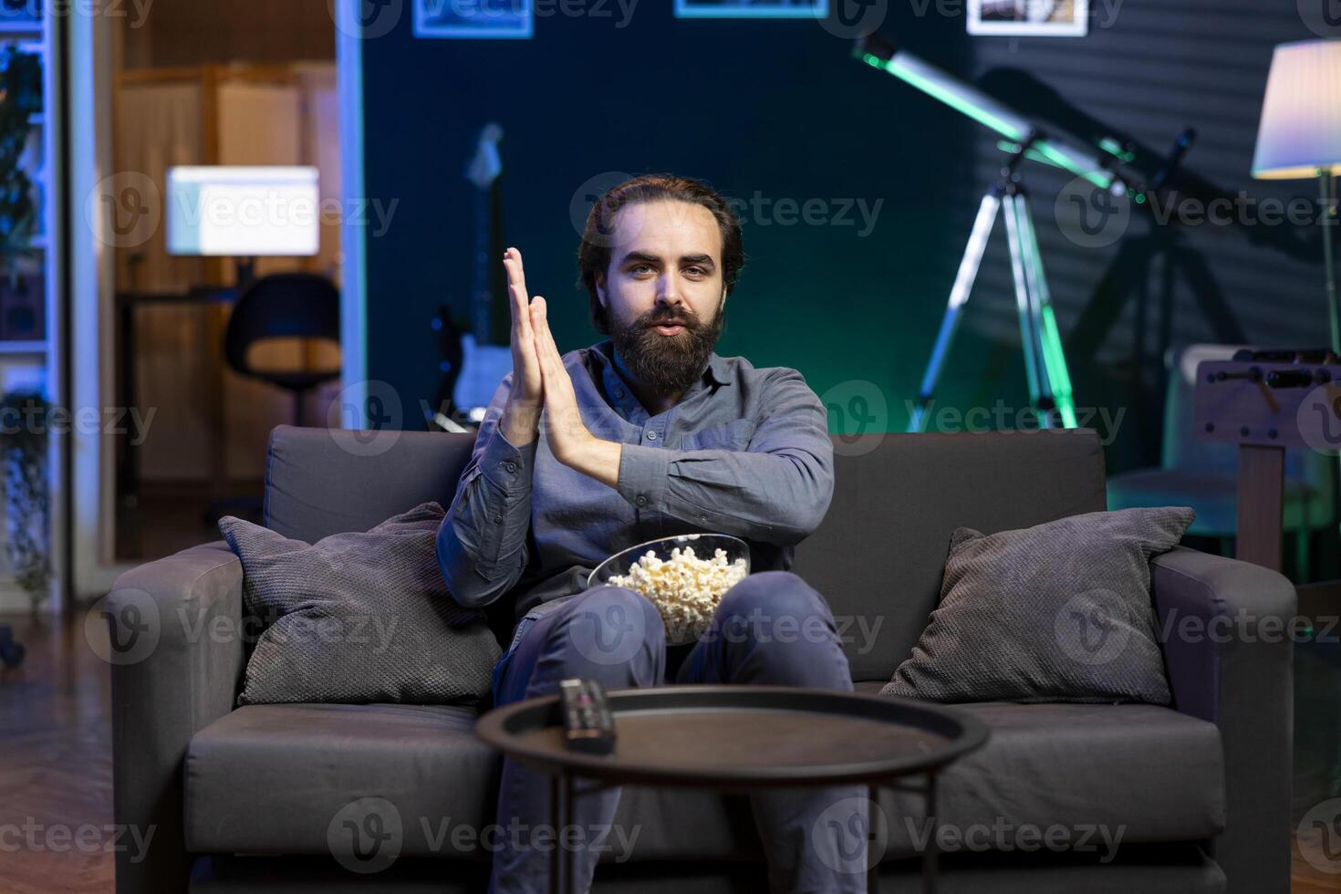 homem fricção mão dentro antecipação, ansioso para Assistir mostra em televisão, comendo Pipoca, pagando fechar atenção para tela. impaciente homem sentado em sofá dentro apartamento, dolorido para pegar favorito televisão Series foto