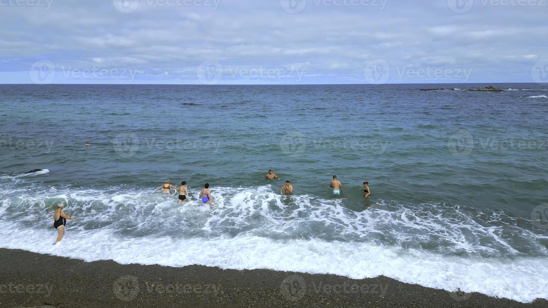 topo Visão do pessoas natação dentro azul água em nublado dia. grampo. lindo azul mar com ondas e flutuando pessoas. turistas nadar e relaxar em lindo mar com azul água foto