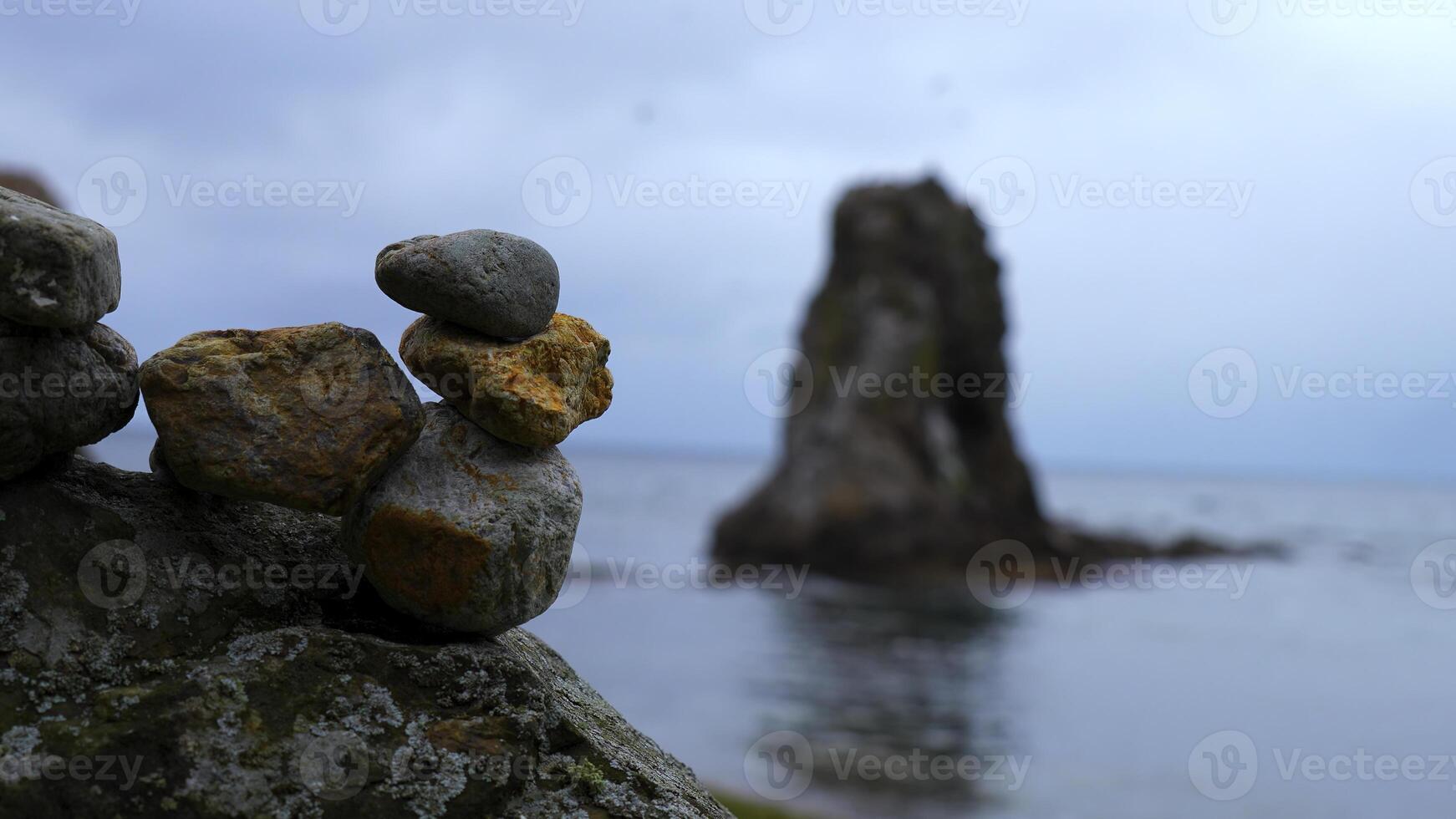 fechar-se do empilhado pedras em de praia com pedras. grampo. pedras empilhado dentro composição em borrado fundo do pedras dentro mar. pedras empilhado dentro torre ficar de pé em fundo do nublado mar foto