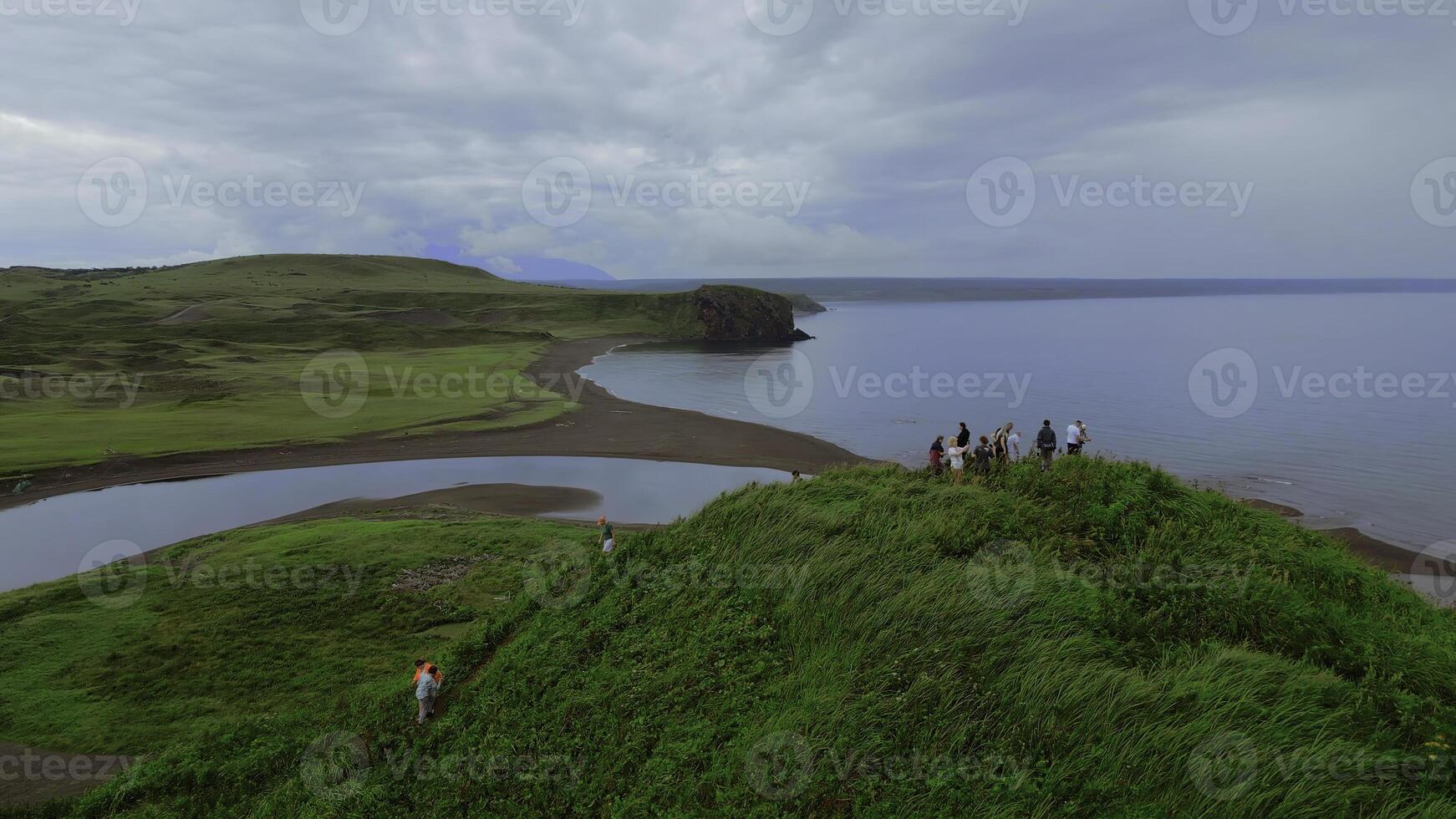 conceito do turismo, grupo do pessoas em a Colina topo. grampo. aéreo Visão do verde Relva e a mar costa. foto