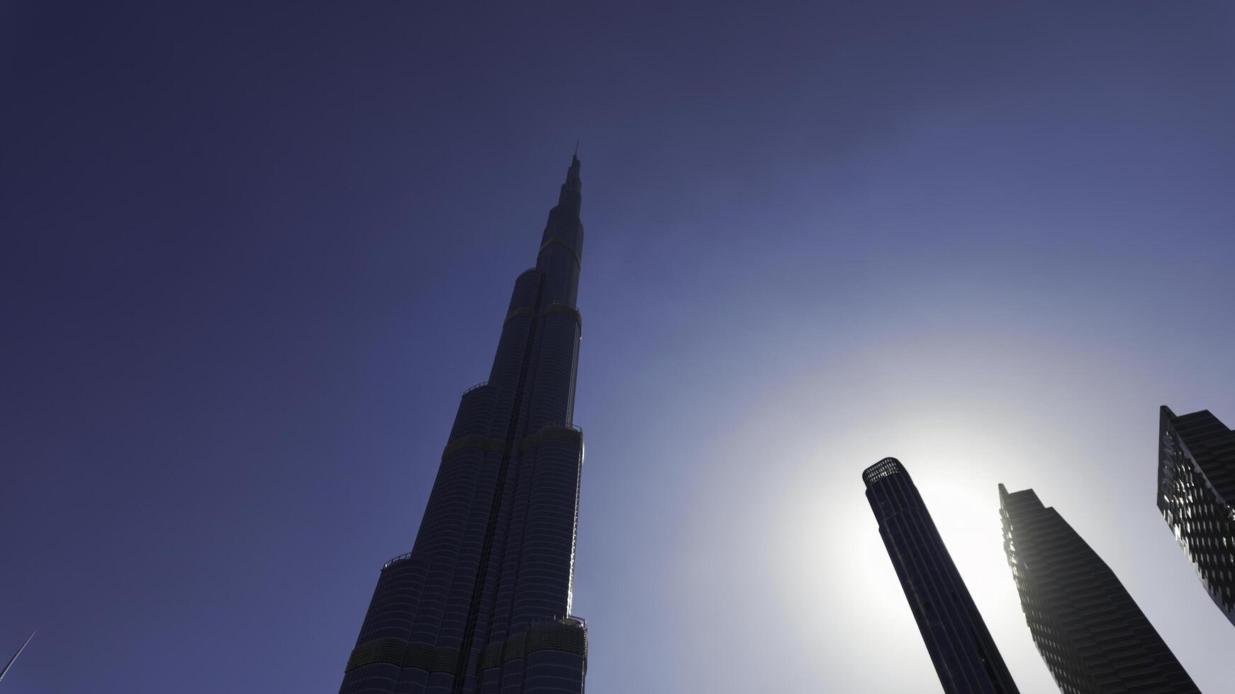 baixo ângulo Visão do burj Khalifa com azul céu atrás. Ação. moderno vidro fachada arranha-céu dentro a cidade Centro. foto