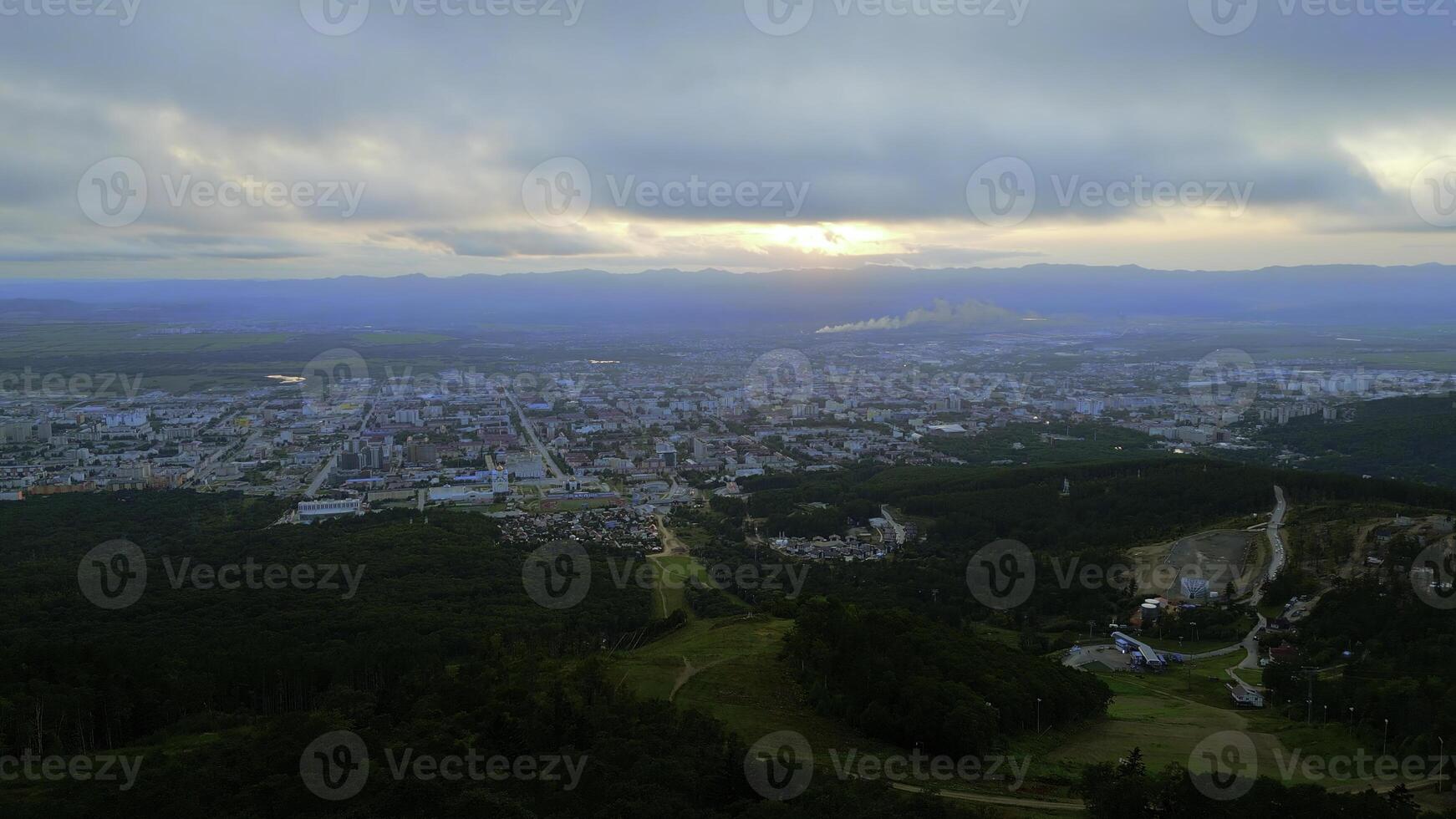 aéreo voar descida a verde montanhas para turista cidade. grampo. verão verde árvores em uma Colina declive e a cidade com nublado céu acima. foto