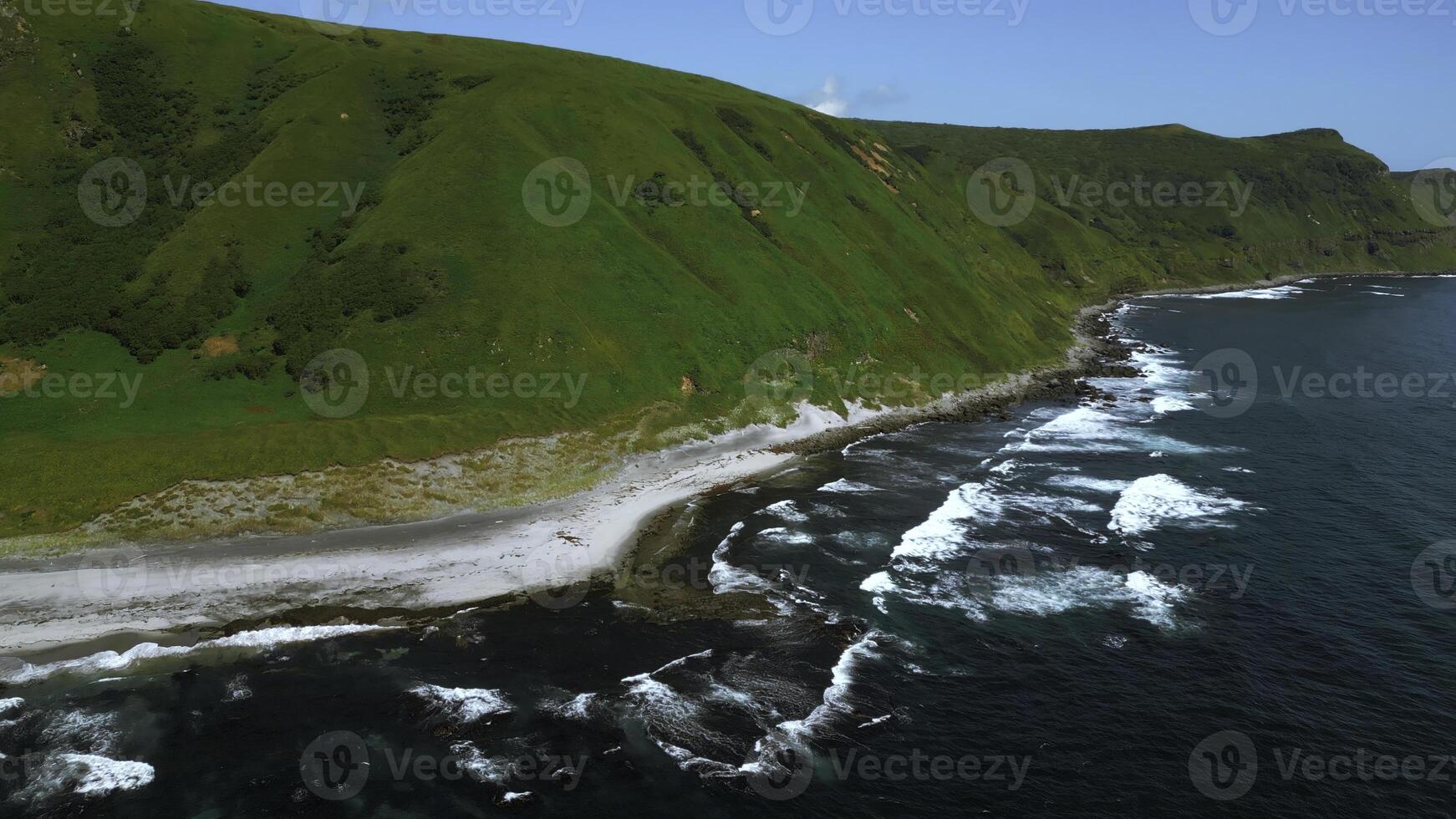 selvagem natureza, verde montanhas com íngreme verde declives conduzindo para a mar. grampo. aéreo do espuma do azul ondas pausa dentro vulcânico pedras. foto