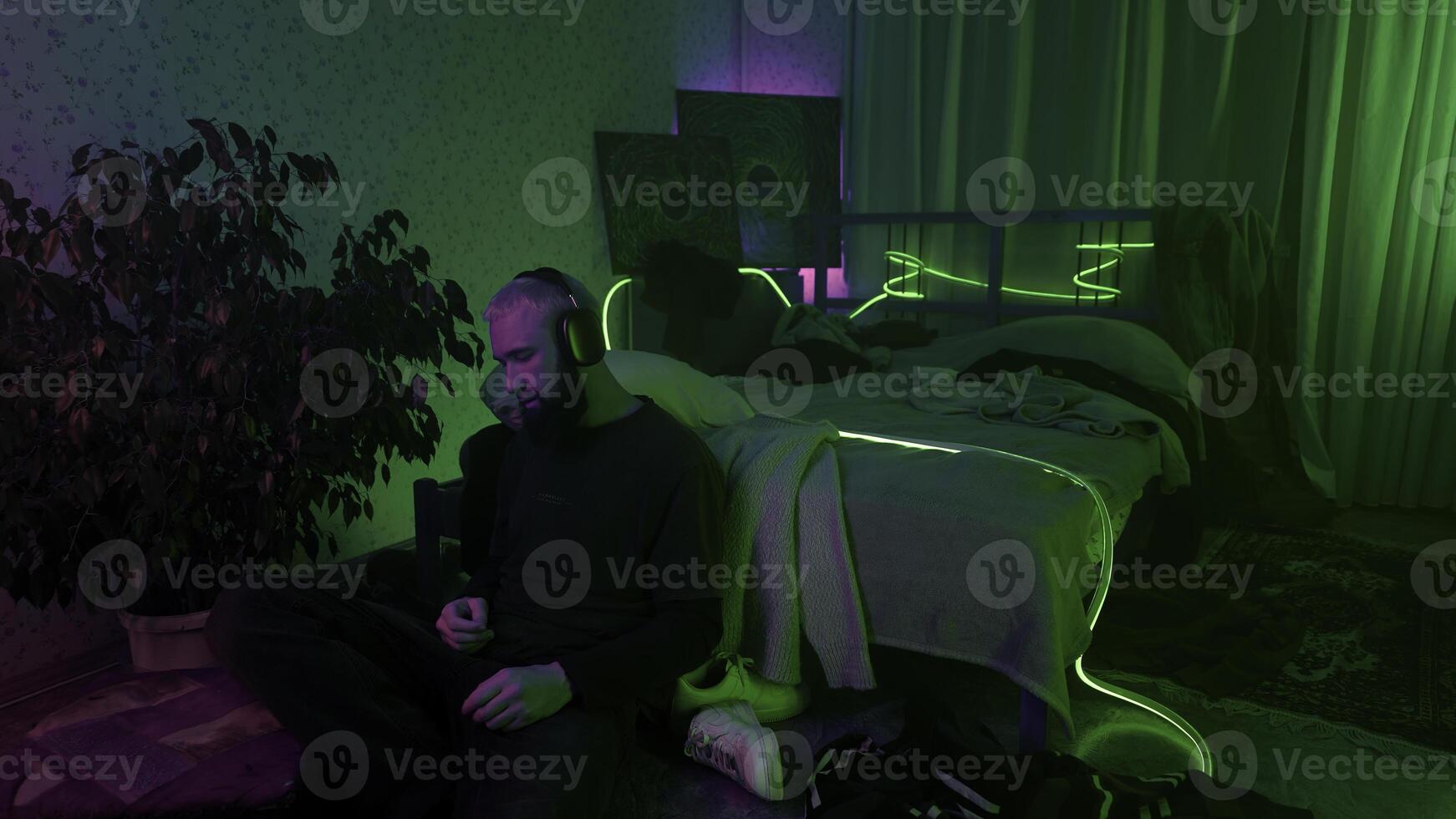 homem usando Smartphone e ouvindo para música às lar. meios de comunicação. acolhedor e bagunçado quarto do uma hipster cara. foto