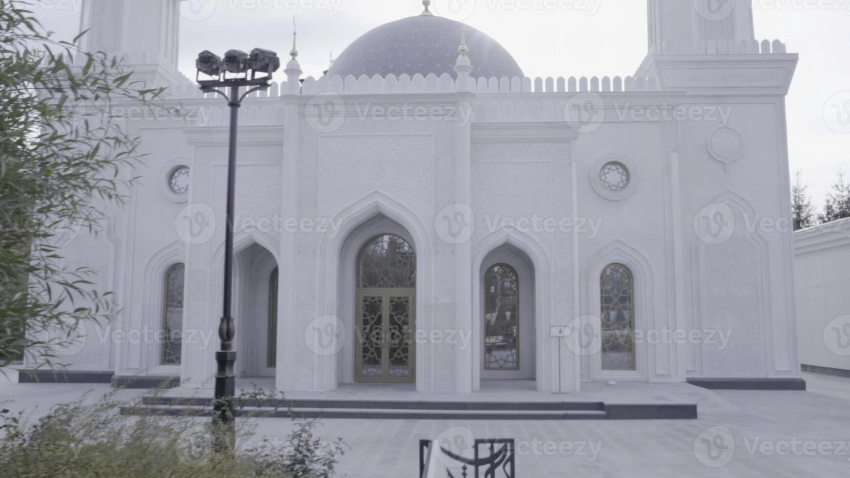 uma branco e cinzento histórico mesquita atrás árvores dentro a cidade. cena. religioso construção com minaretes em nublado céu fundo. foto