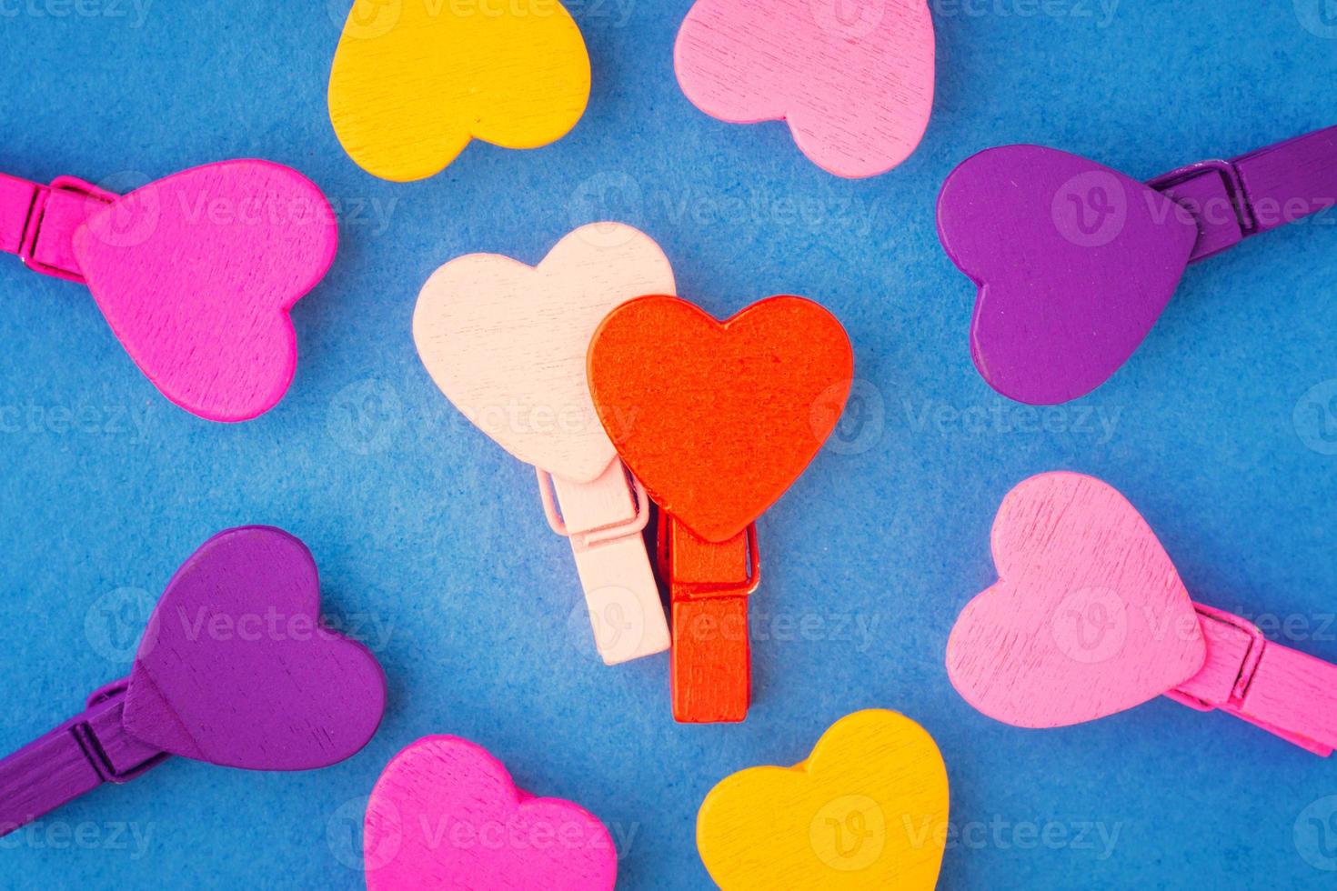 casal apaixonado por corações de madeira cercados por corações coloridos em um fundo azul foto
