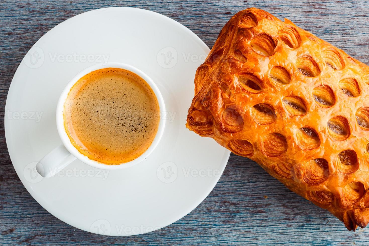 uma xícara de café e um bolo sobre uma mesa de madeira. foto