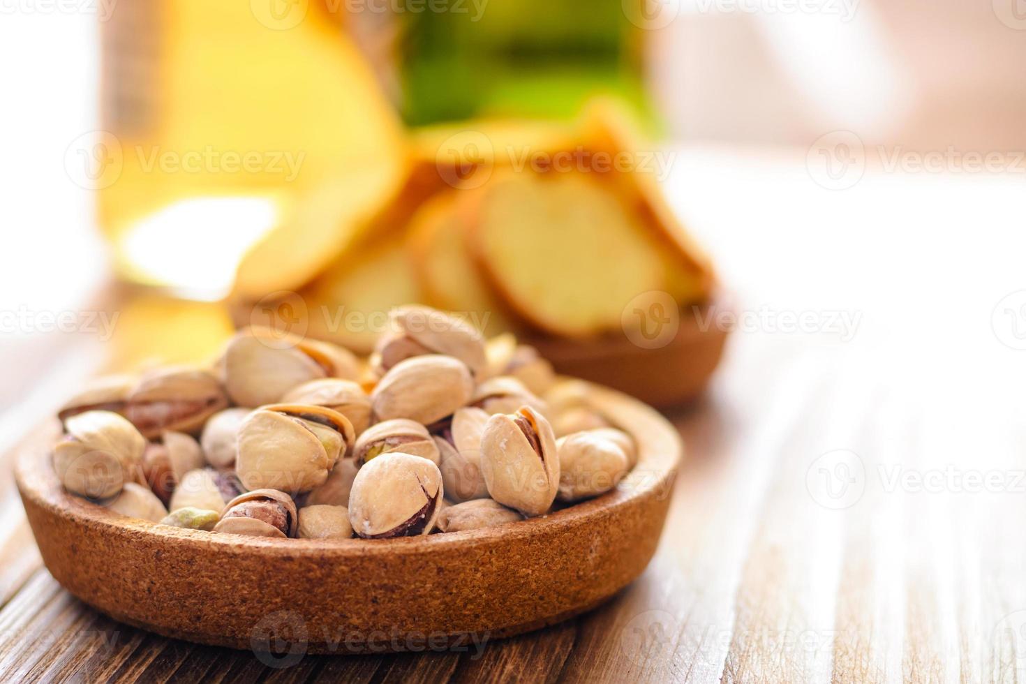 punhado de close-up de pistache salgado e cerveja em uma mesa de madeira foto