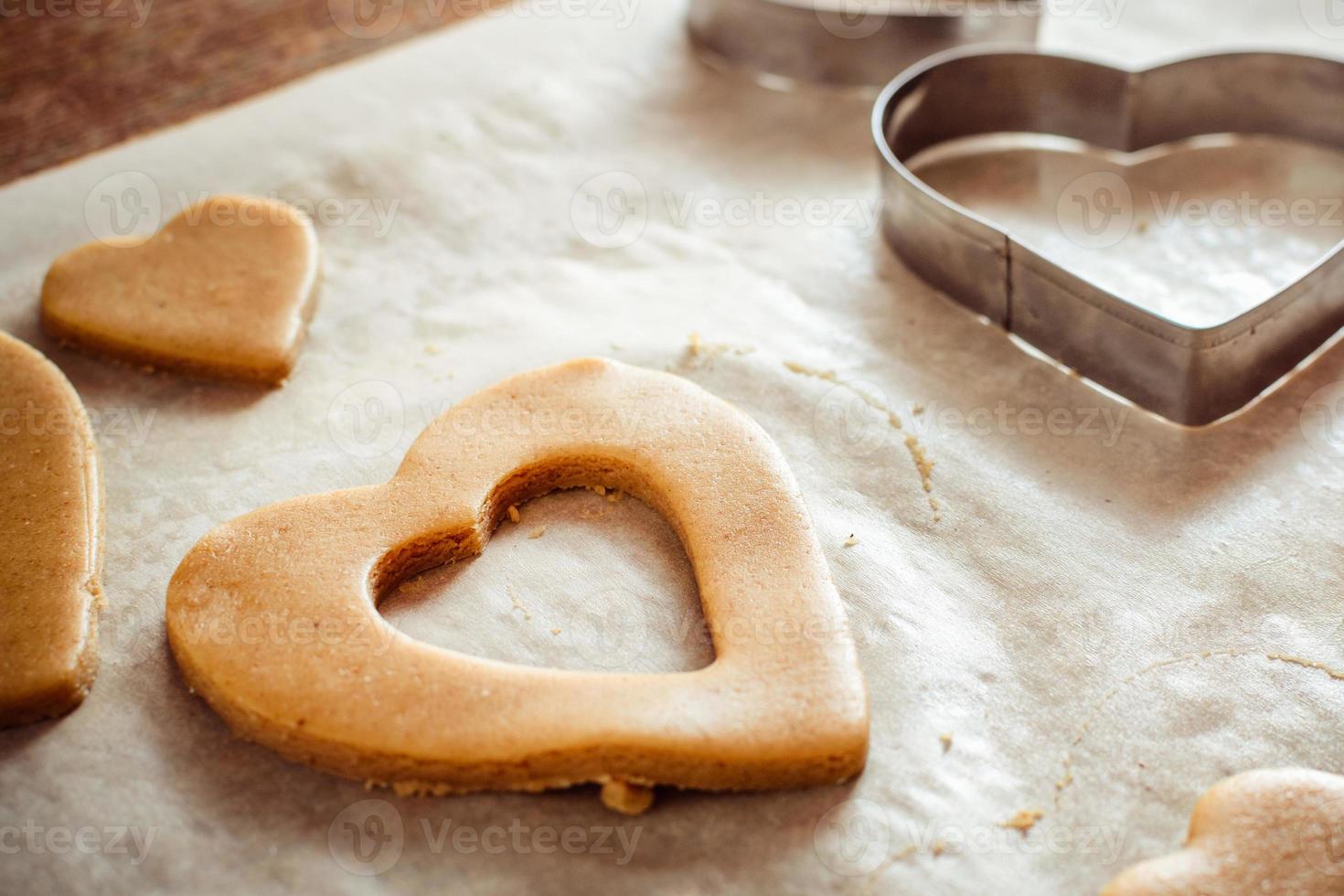 processo de fabricação de biscoitos de gengibre em forma de coração em uma mesa de madeira foto