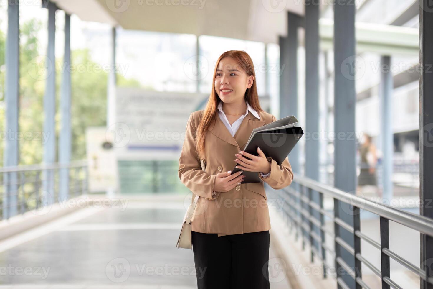jovem lindo bem sucedido o negócio mulher lado de fora escritório prédio, bem sucedido ásia mulher sorridente em pé com documentos foto