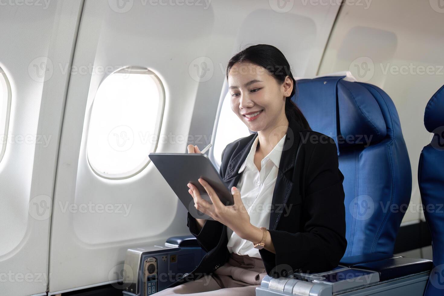 sorridente feliz o negócio mulher ásia vôo e trabalhando dentro a avião dentro primeiro aula, mulher sentado dentro a avião usando digital tábua foto