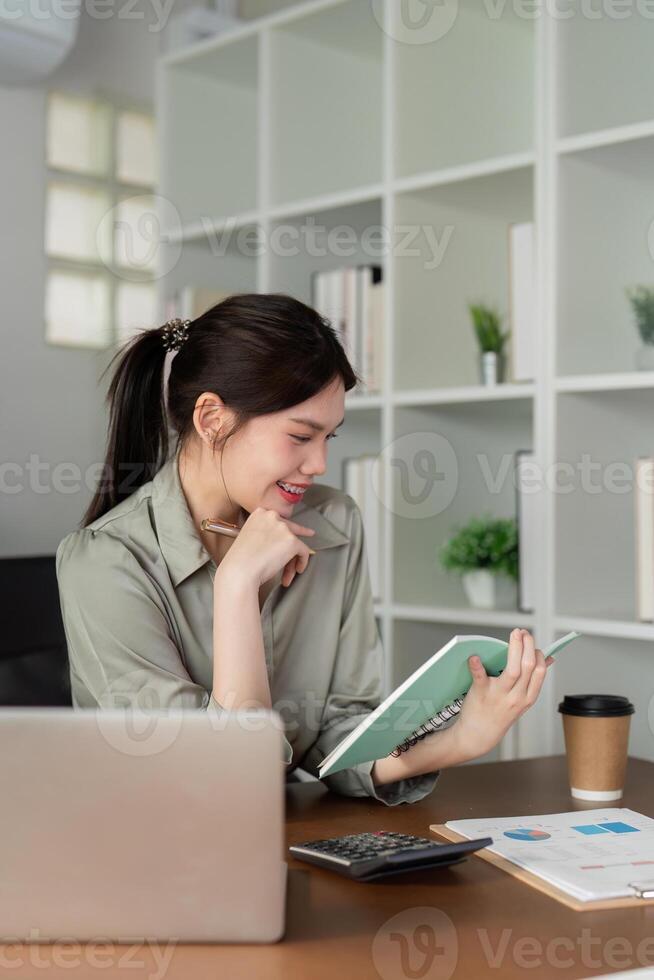 ásia o negócio mulher usando computador portátil para análise gráfico financeiro despesas relatório e planejamento para futuro dentro escritório escrivaninha foto