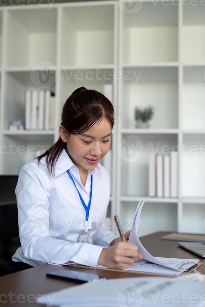 ásia o negócio mulher usando computador portátil para análise gráfico financeiro despesas relatório e planejamento para futuro dentro escritório escrivaninha foto