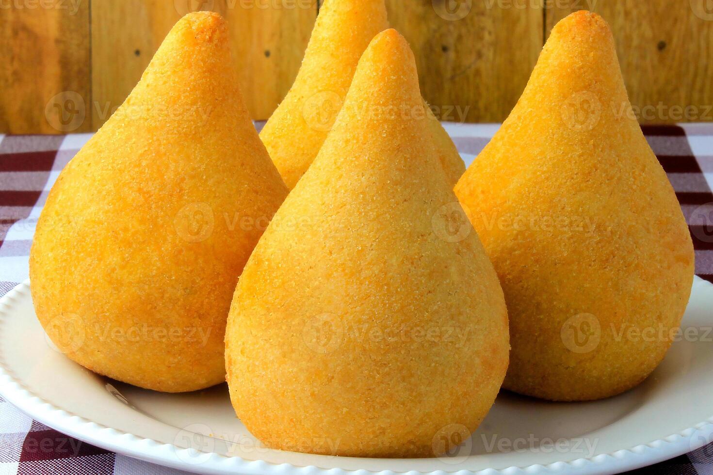 coxinha dentro a prato, tradicional brasileiro cozinha lanches recheado com frango, em rústico de madeira mesa foto