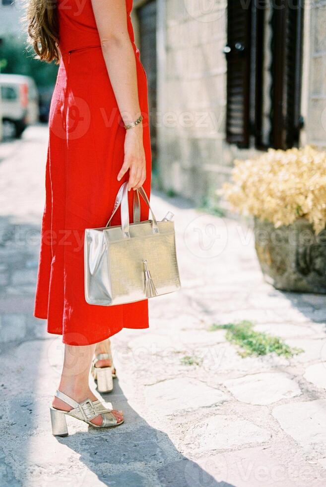 jovem mulher com uma Bolsa dentro dela mão carrinhos meio virado perto a velho casa. cortado. sem rosto foto