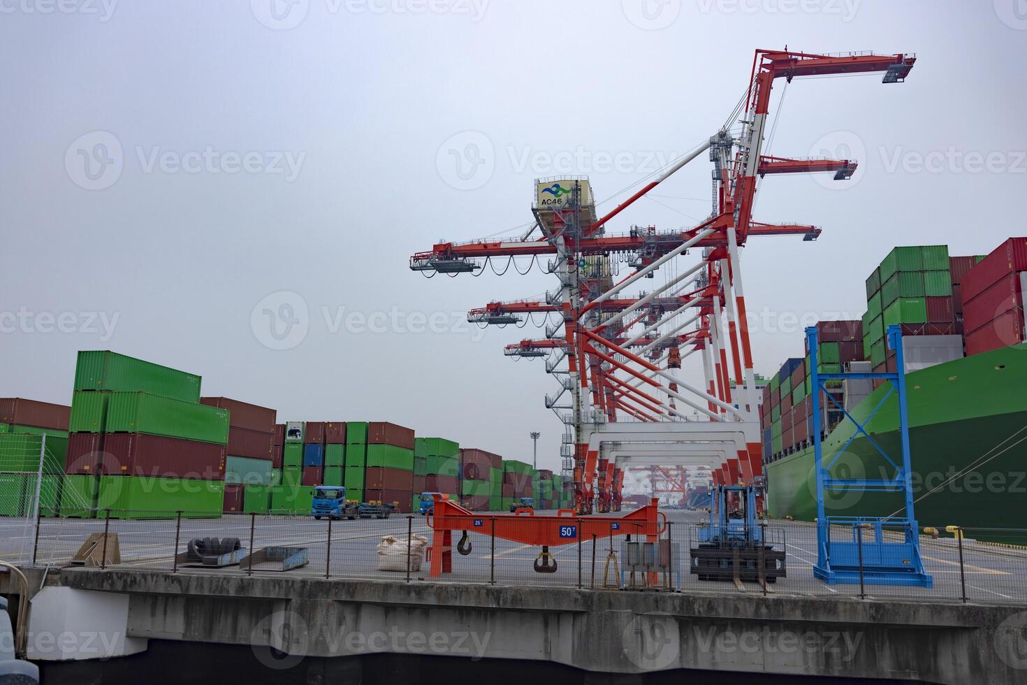 industrial guindastes e uma ampla navio perto a recipiente cais nublado dia Largo tiro foto